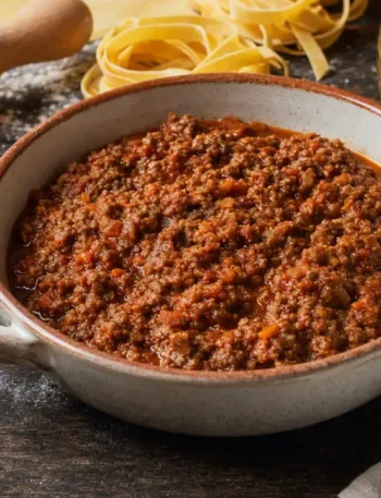 Ragù alla Bolognese tradizionale con tagliatelle fresche all'uovo e ingredienti per la pasta
